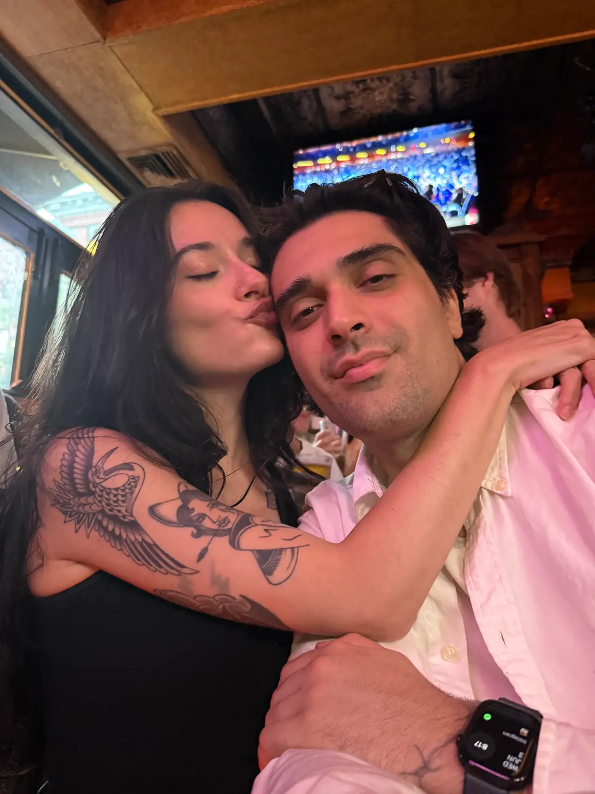 olivia with her arms around thomas, her head against his, the game still on behind them