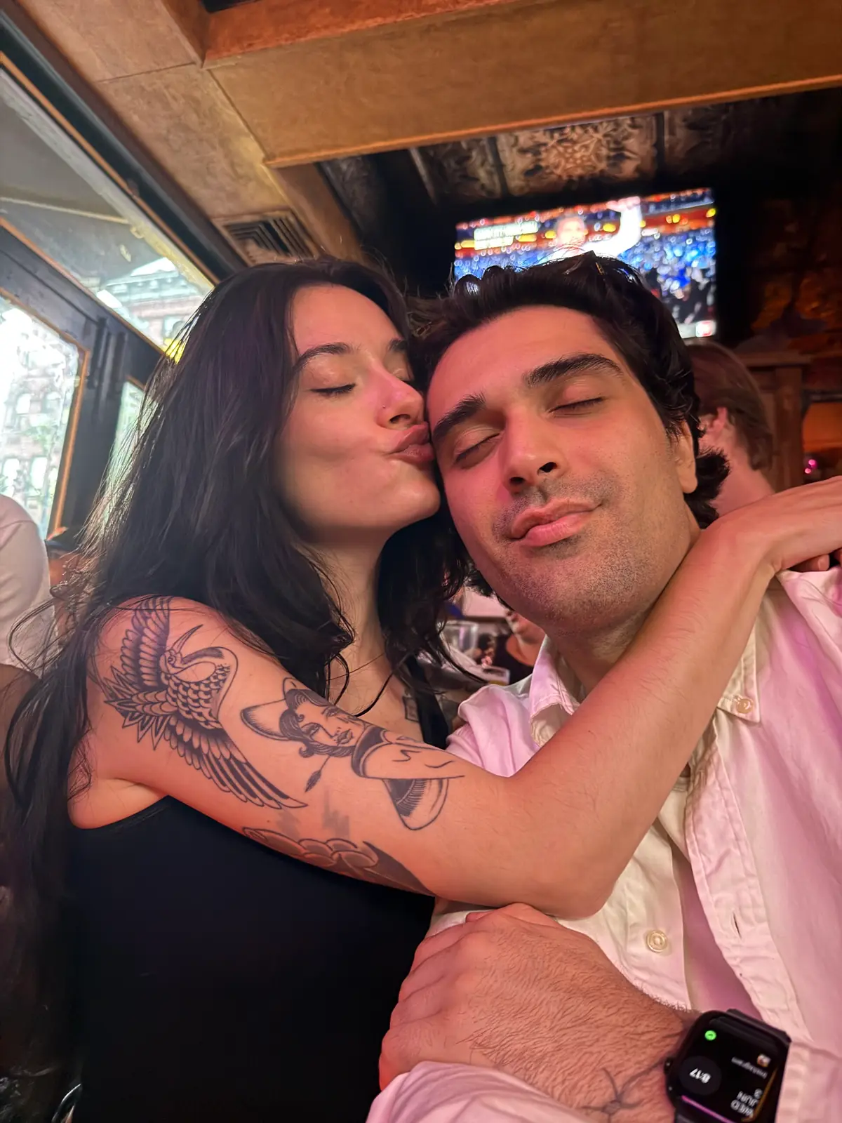 olivia with her arm around my neck, kissing my cheek in a bar, my shirt half untucked