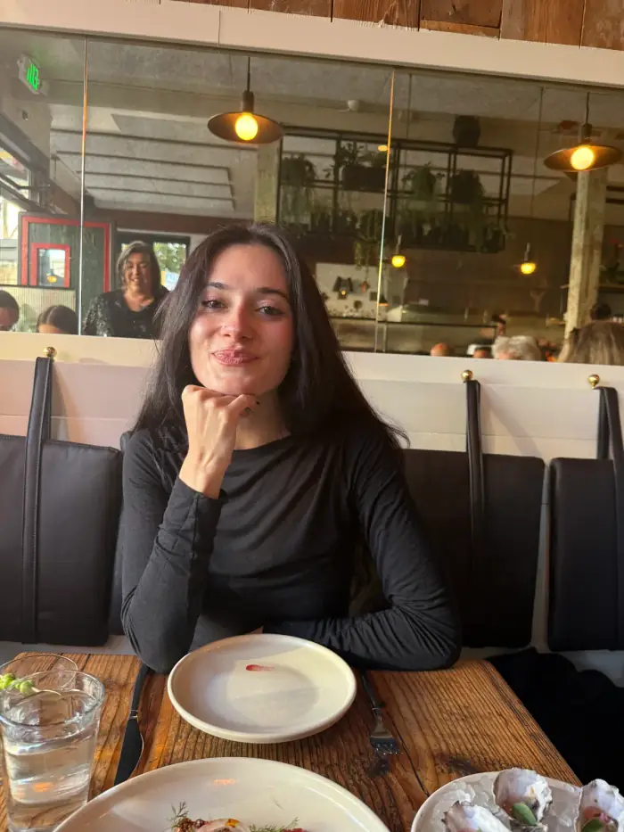 olivia at a cafe table, chin on her hand, empty plate in front of her