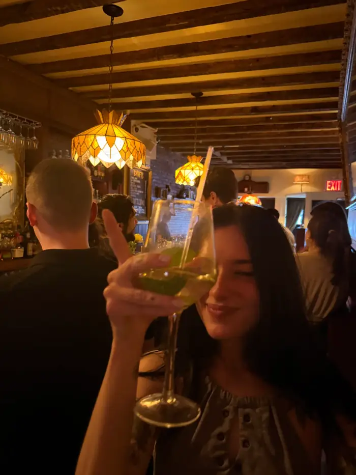 olivia raising a glass in a crowded warm lit bar