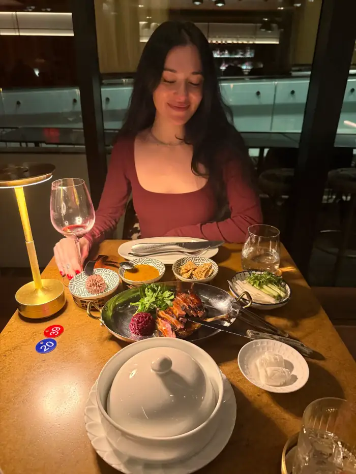 olivia at a dinner table by candlelight, plates and a lit candle in front of her