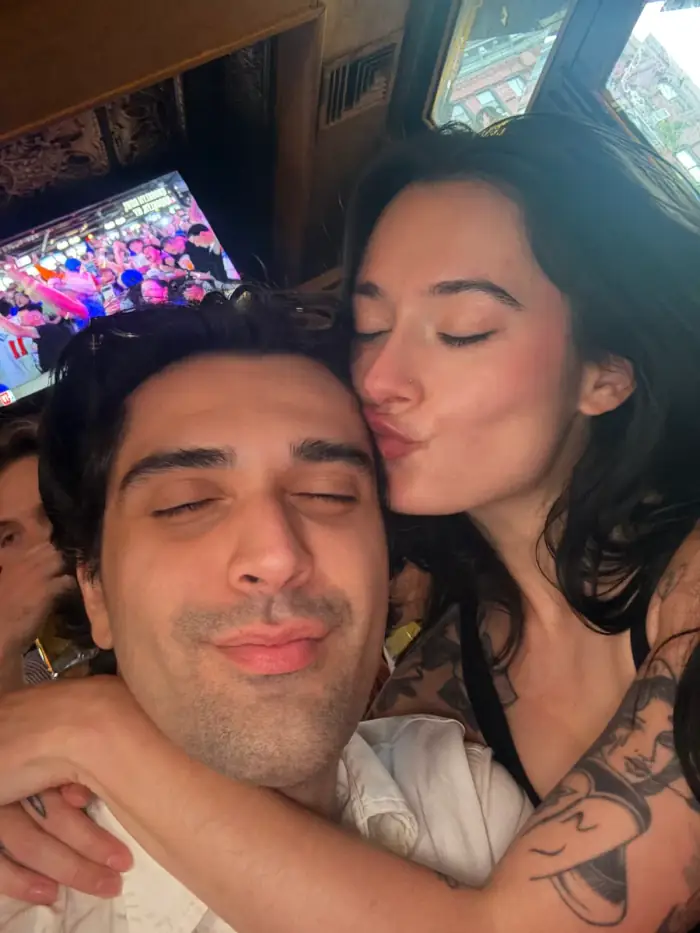 olivia kissing thomas on the cheek at a game, screens behind them