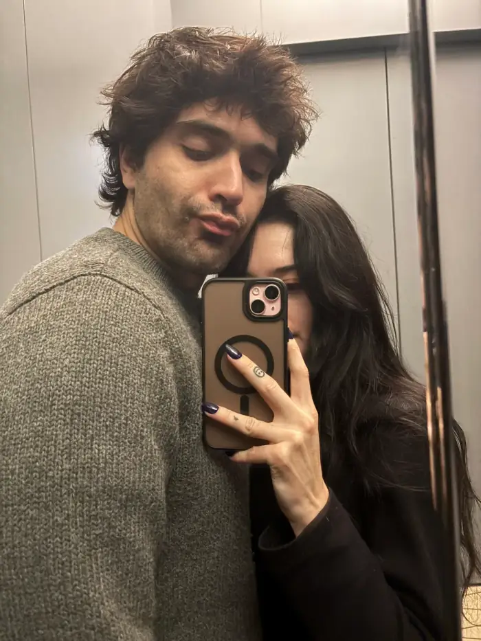 mirror selfie, thomas in a grey sweater with olivia leaning in behind him