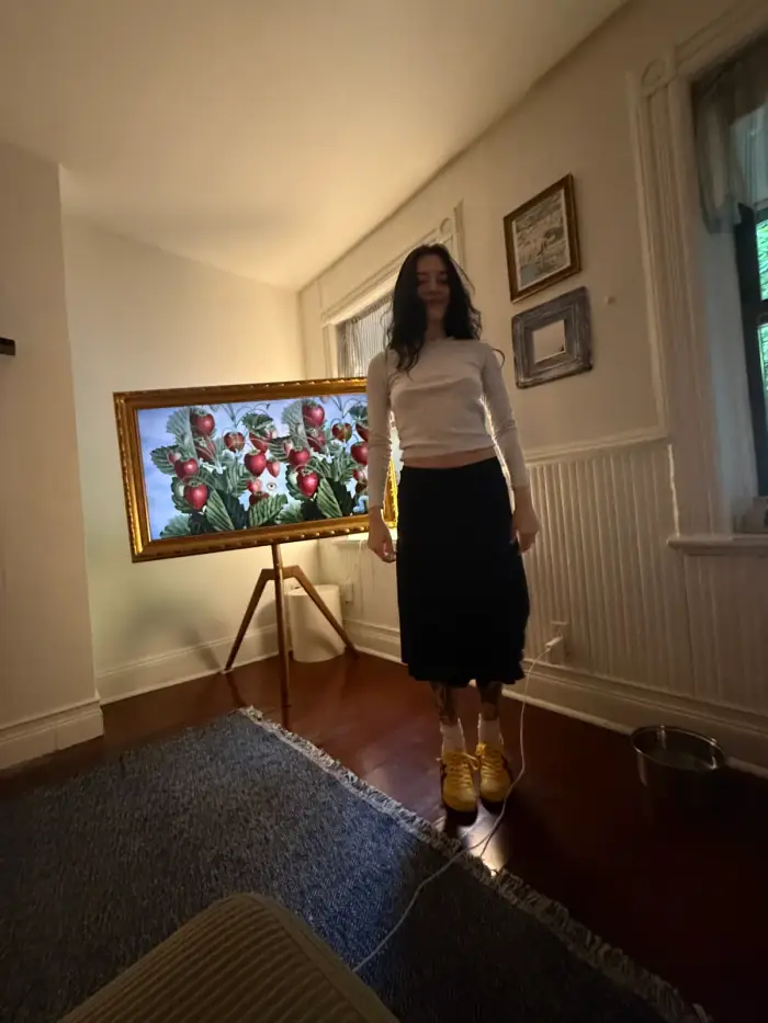 olivia standing in an empty white room beside a large framed painting on an easel