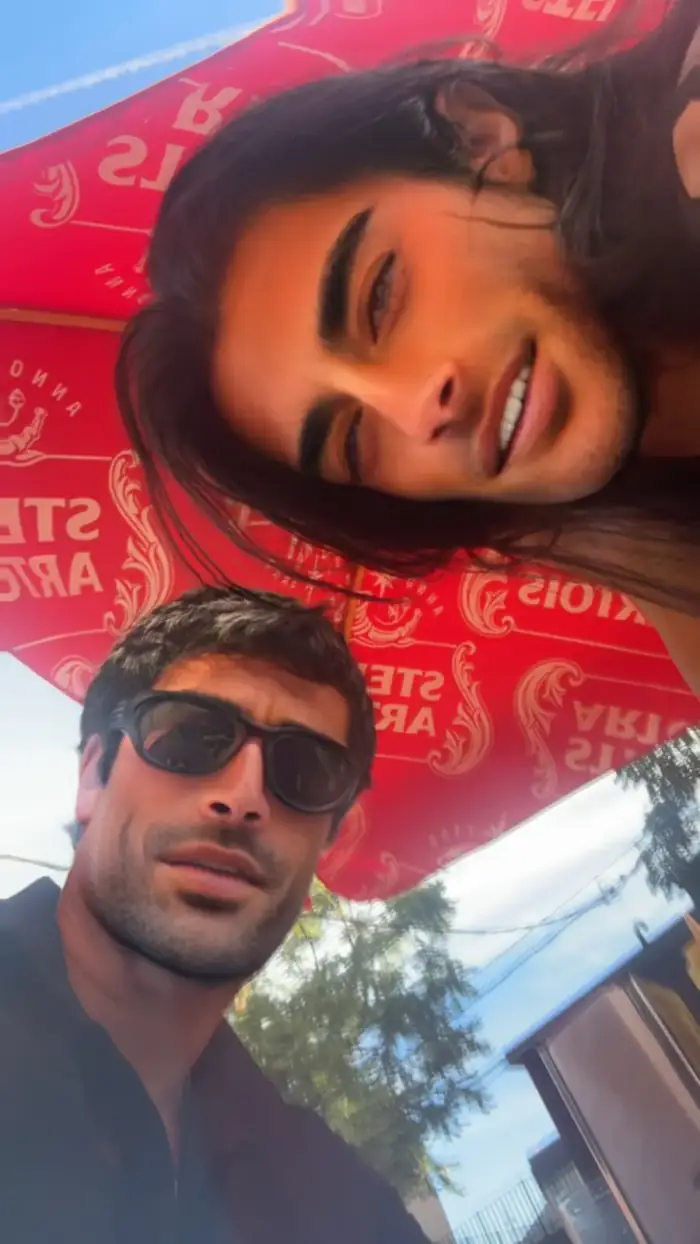 under a red stella artois umbrella, you leaning over me, me in sunglasses