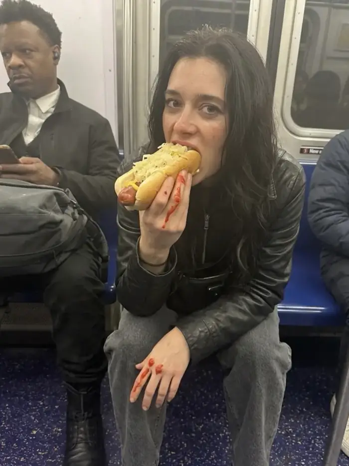 olivia eating a hot dog on the subway with ketchup on her hand